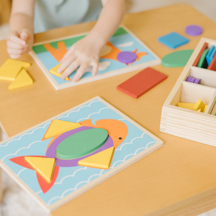 A kid playing with The Melissa & Doug Beginner Wooden Pattern Blocks Educational Toy With 5 Double-Sided Scenes and 30 Shapes