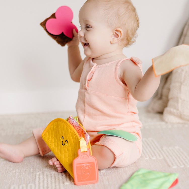 A kid playing with The Melissa & Doug Multi-Sensory Soft Taco Fill & Spill Infant Toy