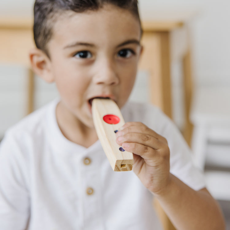 A kid playing with The Melissa & Doug Makin' Music Beginner Wooden Kazoo