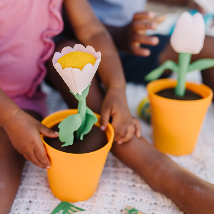 A kid playing with The Melissa & Doug Let’s Explore Flower Gardening Play Set with Color-Changing Flowers (16 Pieces)