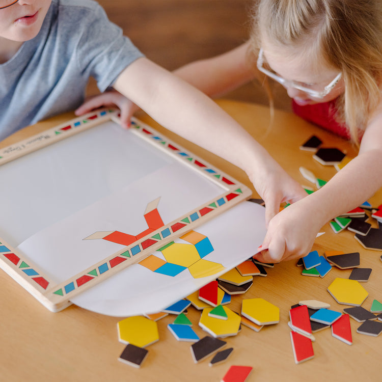 A kid playing with The Melissa & Doug Deluxe Wooden Magnetic Pattern Blocks Set - Educational Toy With 120 Magnets and Carrying Case