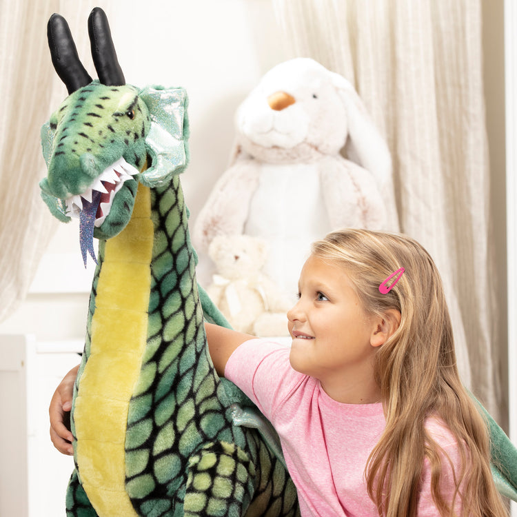 A kid playing with The Melissa & Doug Lifelike Plush Giant Winged Dragon Stuffed Animal (36 x 40.5 x 16 in)