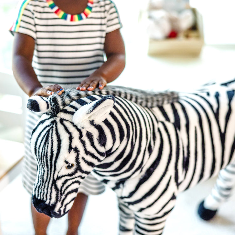 A kid playing with The Melissa & Doug Giant Striped Zebra - Lifelike Stuffed Animal (nearly 3 feet tall)