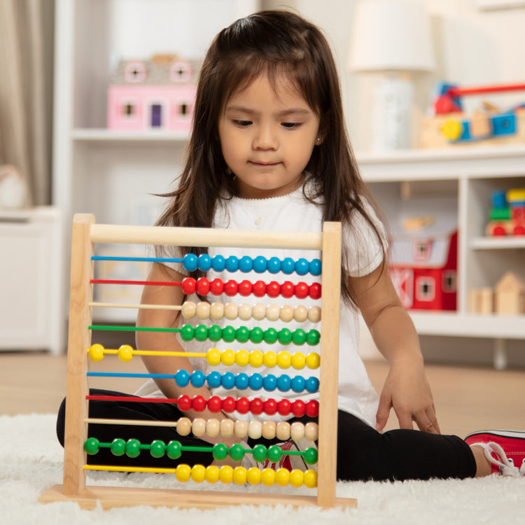 A kid playing with The Melissa & Doug Abacus - Classic Wooden Educational Counting Toy With 100 Beads