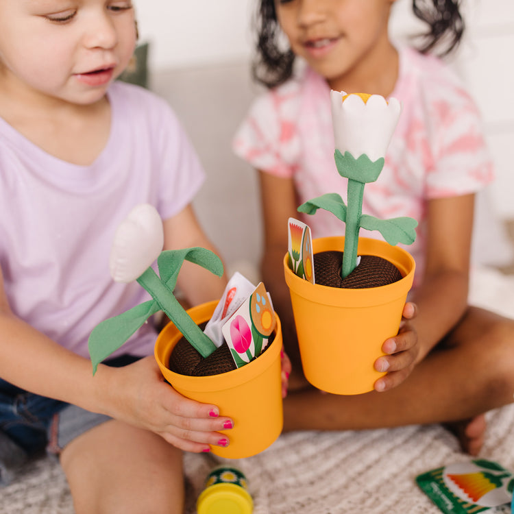 A kid playing with The Melissa & Doug Let’s Explore Flower Gardening Play Set with Color-Changing Flowers (16 Pieces)