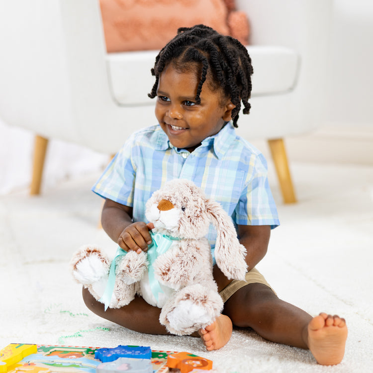 A kid playing with The Melissa & Doug Burrow Bunny Rabbit Stuffed Animal (9 inches)