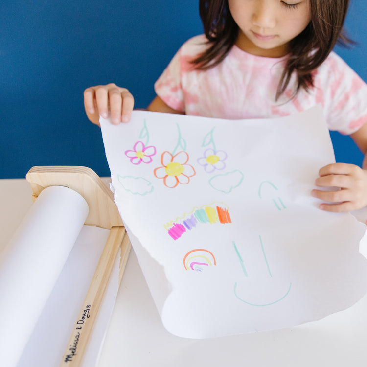 A kid playing with The Melissa & Doug Tabletop Easel Paper Roll (12 inches x 75 feet), 3-Pack