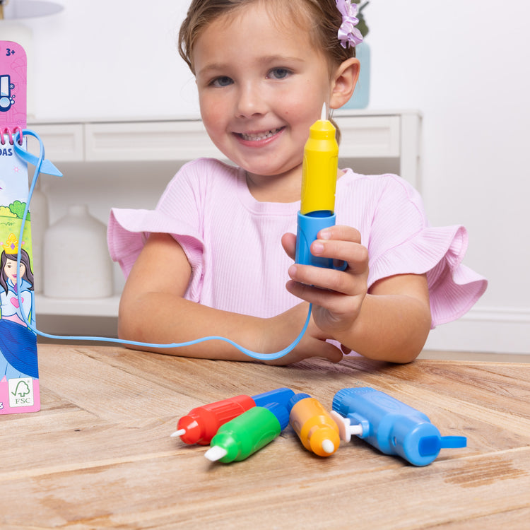 A kid playing with The Melissa & Doug Water WOW! Pen Pack - 4 Color-with-Water Pens, Sprayer, Tether Cap