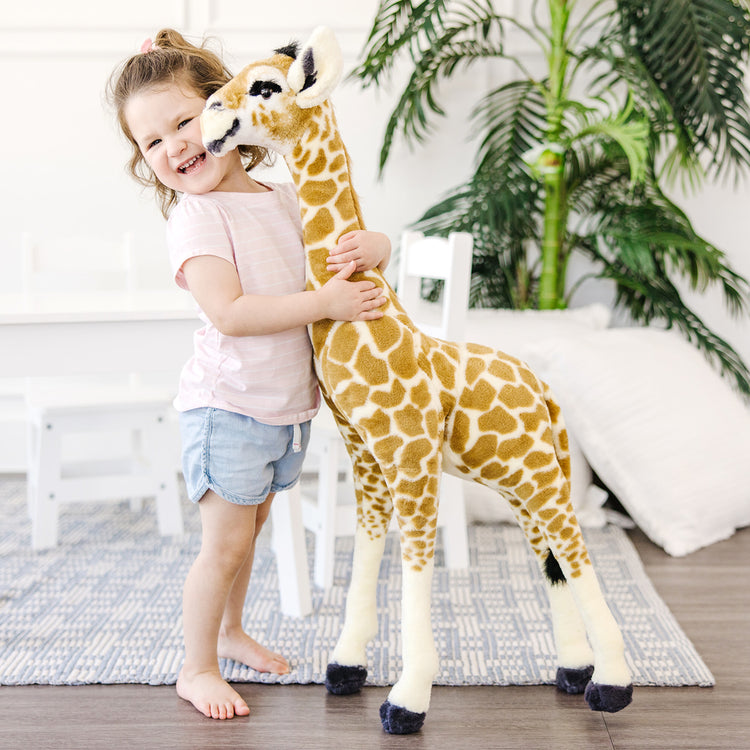 A kid playing with The Melissa & Doug Lifelike Plush Standing Baby Giraffe Stuffed Animal – 3 Feet Tall