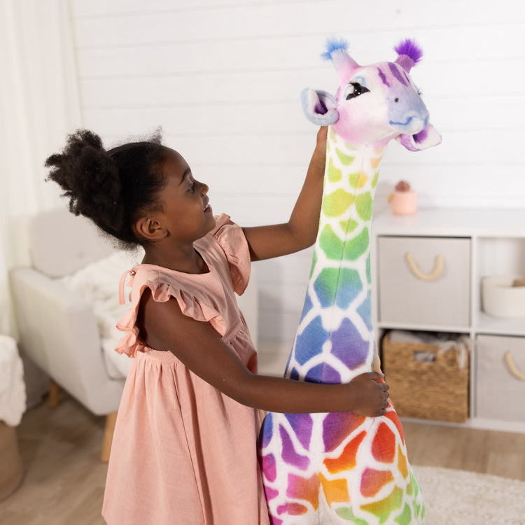 A kid playing with The Melissa & Doug Rainbow Giraffe Lifelike Plush