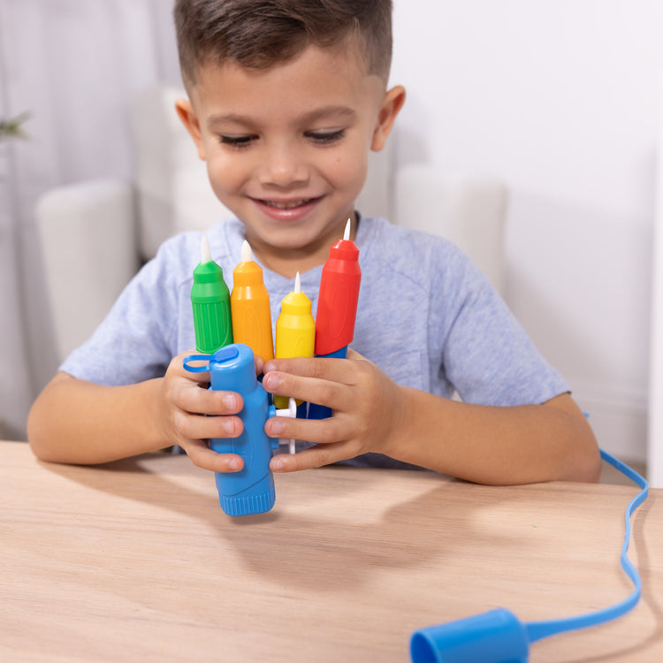 A kid playing with The Melissa & Doug Water WOW! Pen Pack - 4 Color-with-Water Pens, Sprayer, Tether Cap