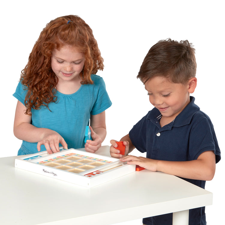 A child on white background with The Melissa & Doug Wooden Tic-Tac-Toe Board Game with 10 Self-Storing Wooden Game Pieces (12.5” W x 8.5” L x 1.25” D)