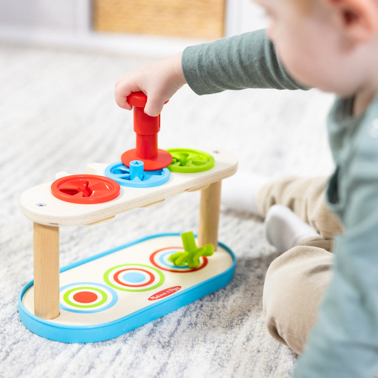 A kid playing with The Melissa & Doug Match & Push Spinning Tops Developmental Skills Toy for Girls and Boys 2+ 