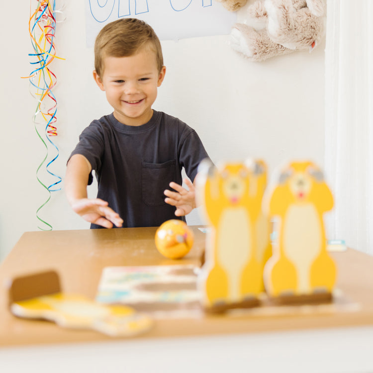 A kid playing with The Melissa & Doug Fun at the Fair! Wooden Armadillo Roll & Bowl Prairie Dog Bowling Game