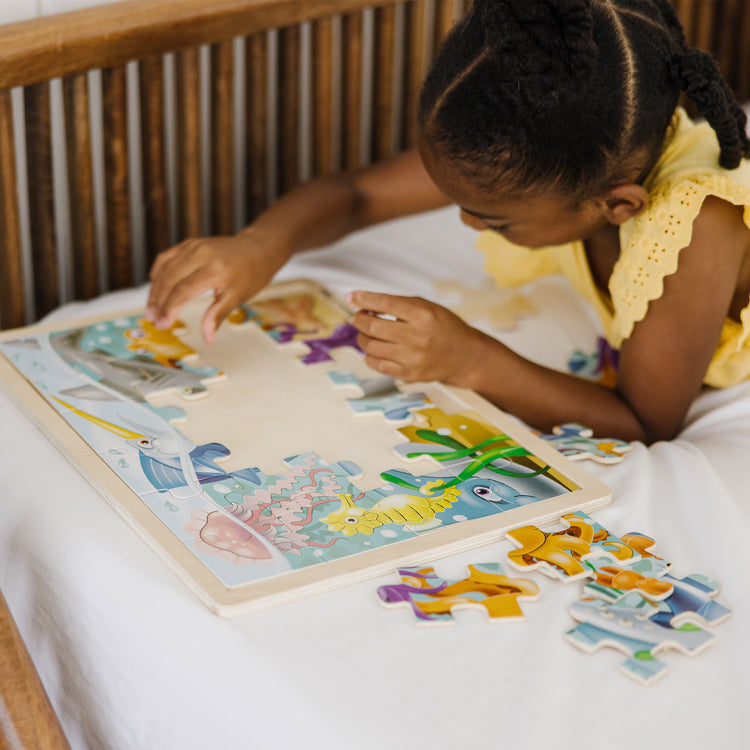 A kid playing with The Melissa & Doug Under the Sea Ocean Animals Wooden Jigsaw Puzzle With Storage Tray (24 pcs)