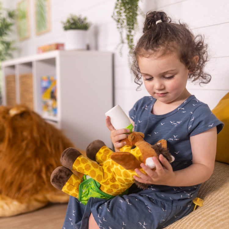 A kid playing with The Melissa & Doug 11-Inch Baby Giraffe Plush Stuffed Animal with Pacifier, Diaper, Baby Bottle