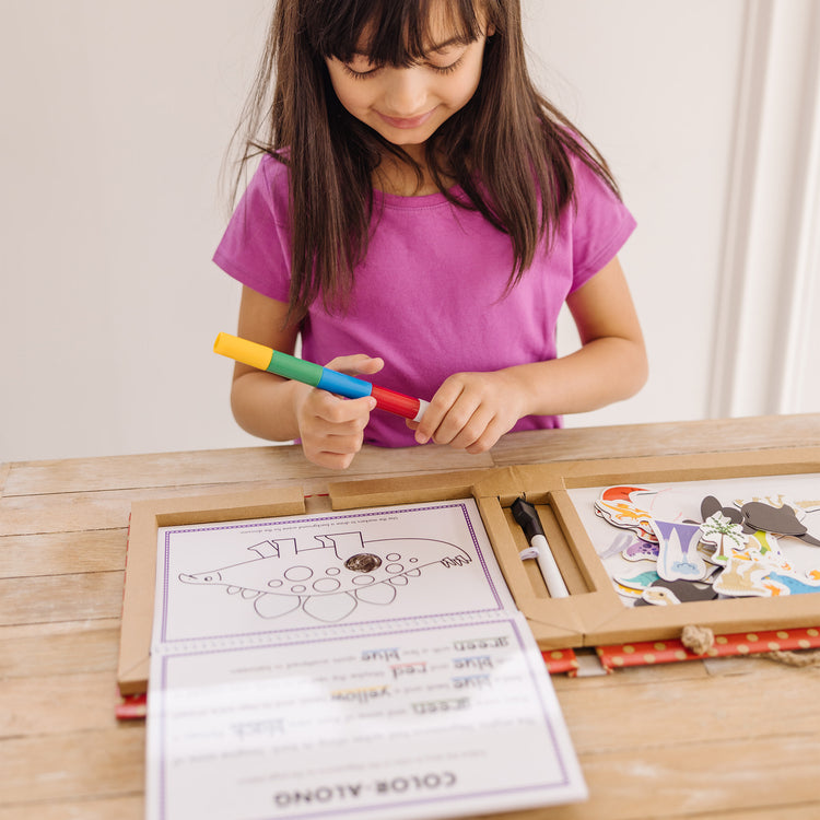 A kid playing with The Melissa & Doug Natural Play: Play, Draw, Create Dinosaurs Drawing Activity Set & Magnet Kit - Reusable Mess-Free Travel Activity