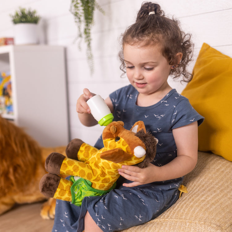 A kid playing with The Melissa & Doug 11-Inch Baby Giraffe Plush Stuffed Animal with Pacifier, Diaper, Baby Bottle