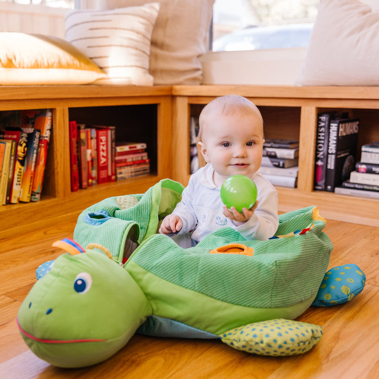 A kid playing with The Melissa & Doug K's Kids Turtle Ball Pit With 60 Balls