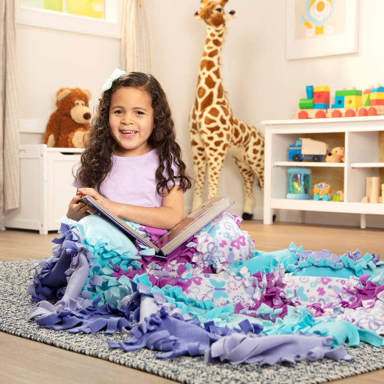 A kid playing with The Melissa & Doug Created by Me! Butterfly Fleece Quilt No-Sew Craft Kit (48 squares, 4 feet x 5 feet)