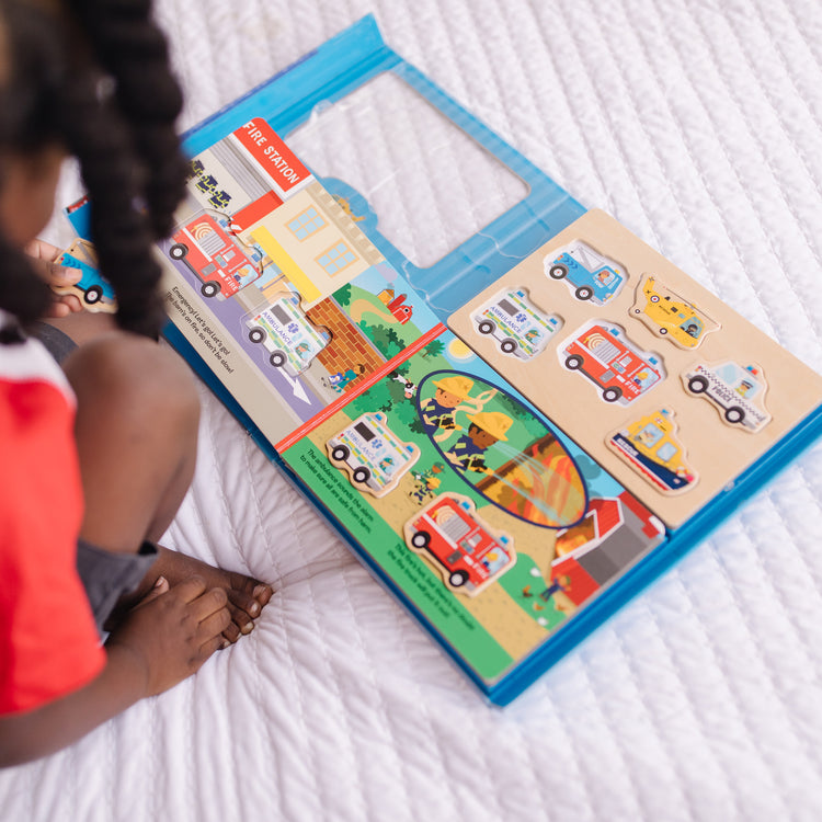 A kid playing with The Melissa & Doug To the Rescue Book and Wooden 6-Piece Puzzle Play Set