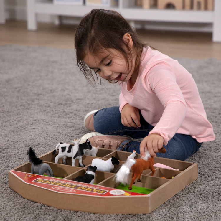 A kid playing with The Melissa & Doug Farm Friends Collectible Toy Animal Figures (10 pcs)