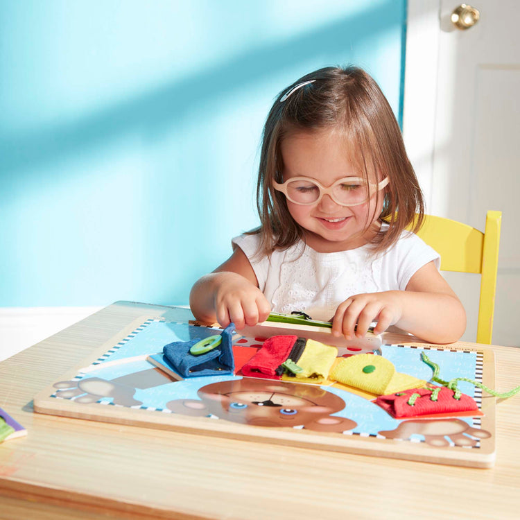 A kid playing with The Melissa & Doug Basic Skills Puzzle Board - Wooden Educational Toy