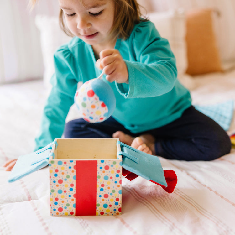 A kid playing with The Melissa & Doug Wooden Surprise Gift Box Infant Toy (5 Pieces)