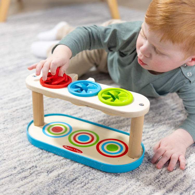 A kid playing with The Melissa & Doug Match & Push Spinning Tops Wooden Developmental Skills Learning Toy for Girls and Boys 2+ 