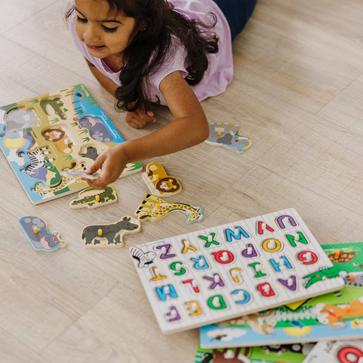 A kid playing with The Melissa & Doug Wooden Peg Puzzle 6-Pack – Numbers, Letters, 3 Animals, Vehicles