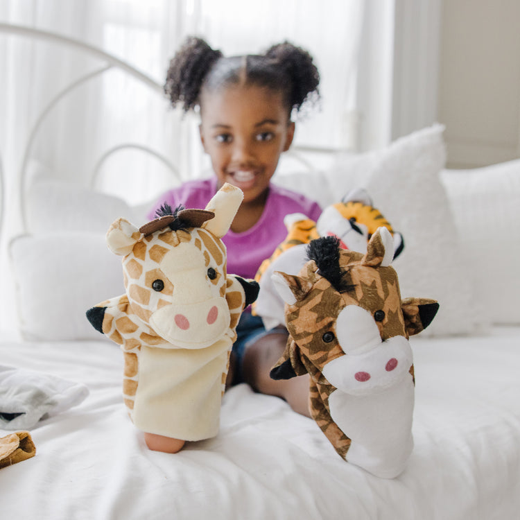 A kid playing with The Melissa & Doug Animal Hand Puppets 2-Pack (4 animals in each) - Zoo Friends and Farm Friends