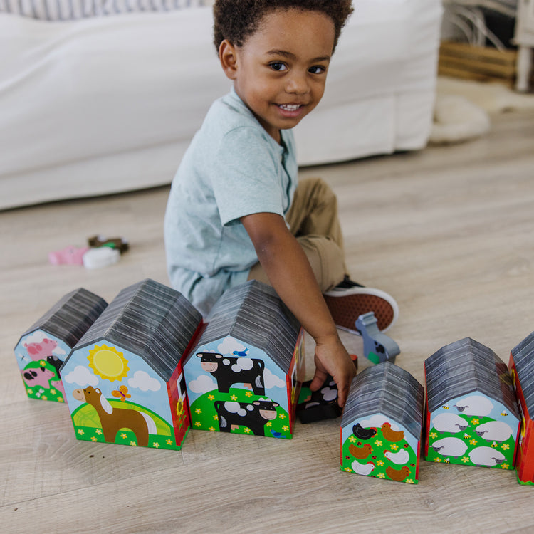 A kid playing with The Melissa & Doug Nesting and Sorting Barns and Animals With 6 Numbered Barns and Matching Wooden Animals