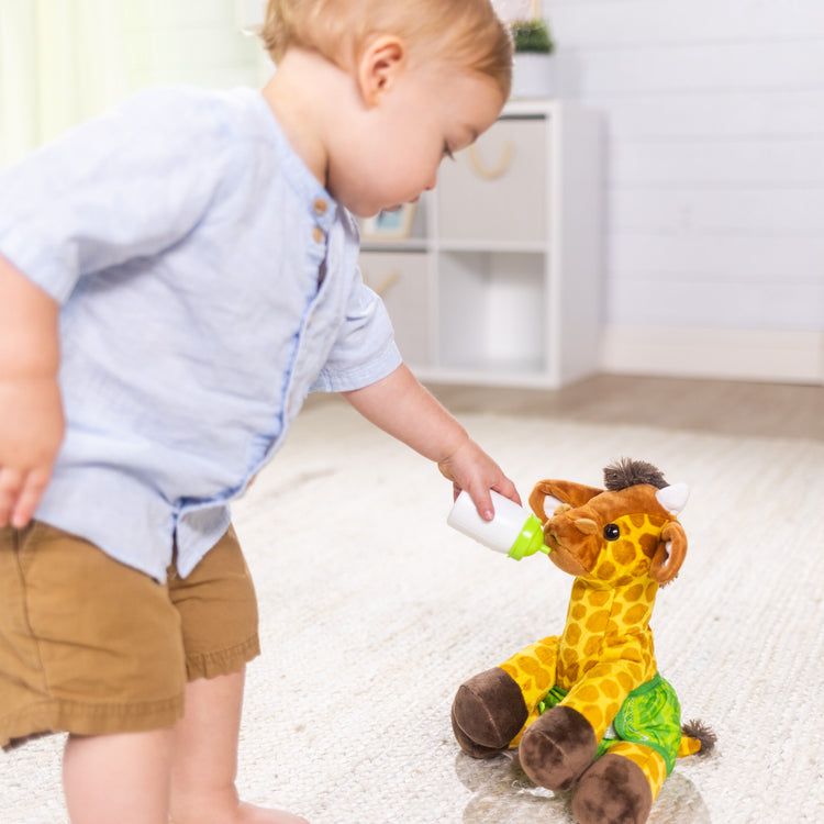 A kid playing with The Melissa & Doug 11-Inch Baby Giraffe Plush Stuffed Animal with Pacifier, Diaper, Baby Bottle