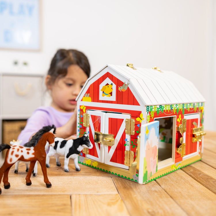 A kid playing with The Melissa & Doug Latches Wooden Activity Barn with 5 Doors, 4 Play Figure Farm Animals