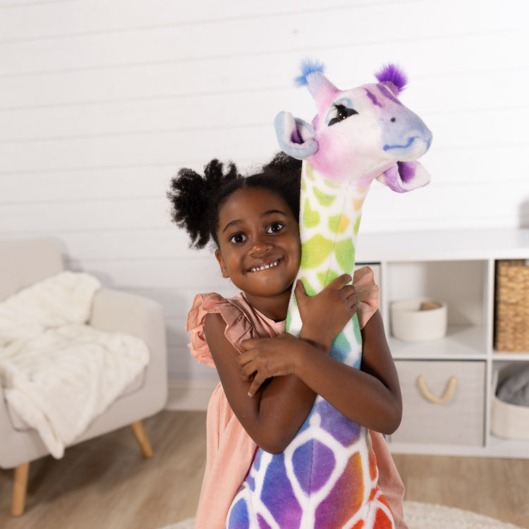 A kid playing with The Melissa & Doug Rainbow Giraffe Lifelike Plush