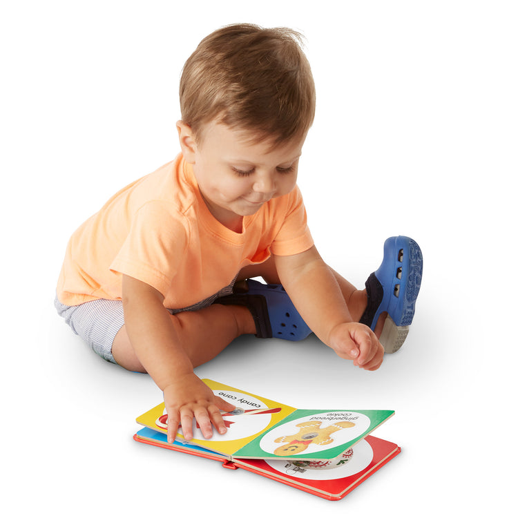 A child on white background with The Melissa & Doug Children’s Book – Poke-a-Dot: Christmas (Board Book with Buttons to Pop)