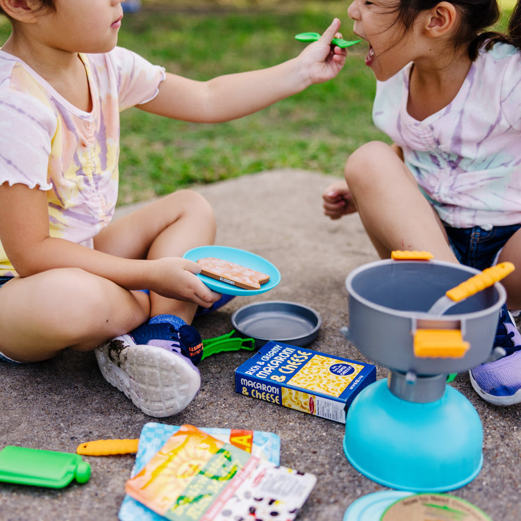 A kid playing with The Melissa & Doug Let’s Explore Outdoor Cooking Play Set – 27 Pieces