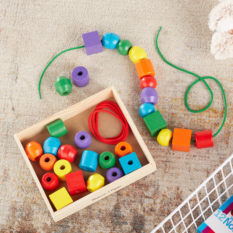 A playroom scene with The Melissa & Doug Primary Lacing Beads - Educational Toy With 30 Wooden Beads and 2 Laces