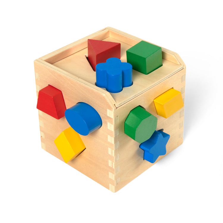 A kid playing with The Melissa & Doug Shape Sorting Cube - Classic Wooden Toy With 12 Shapes