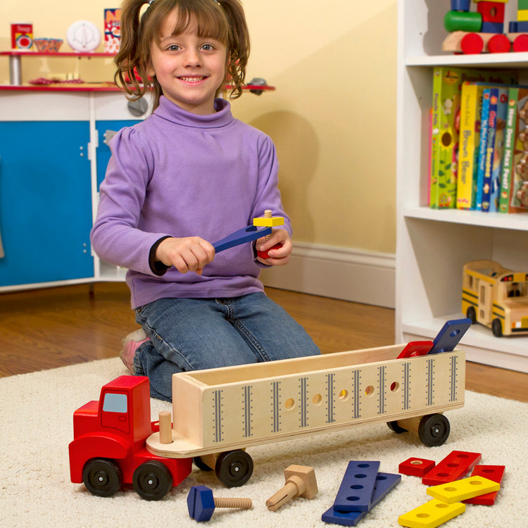 A kid playing with The Melissa & Doug Wooden Big Rig Truck Building Set (22 pcs)