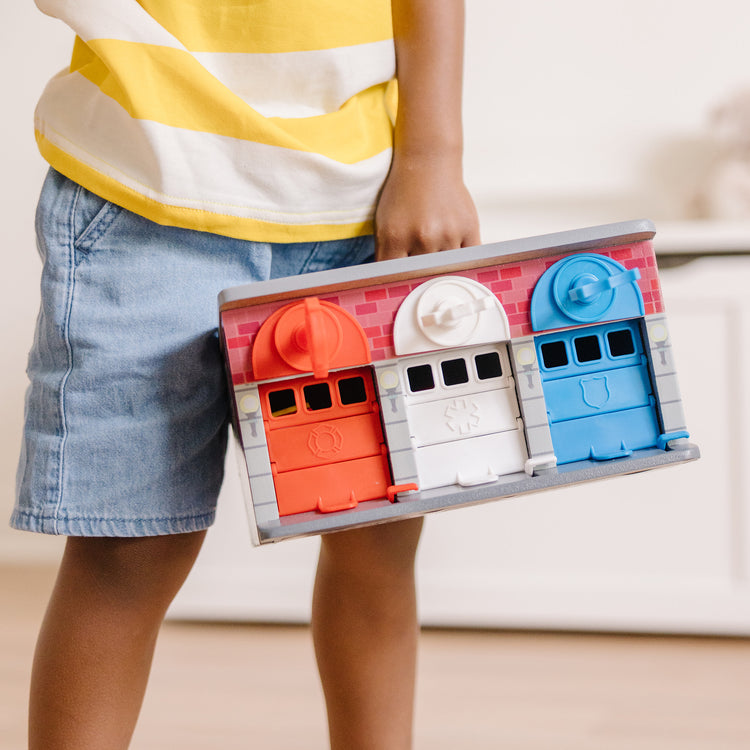 A kid playing with The Melissa & Doug Toy Keys and Cars Wooden Rescue Vehicles and Garage (7 pcs)