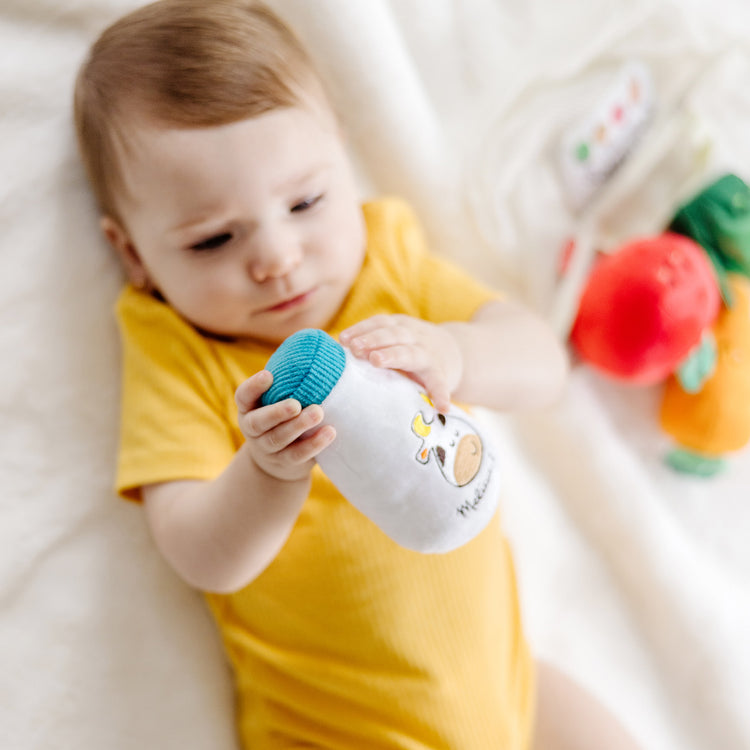 A kid playing with The Melissa & Doug Multi-Sensory Market Basket Fill & Spill Infant Toy