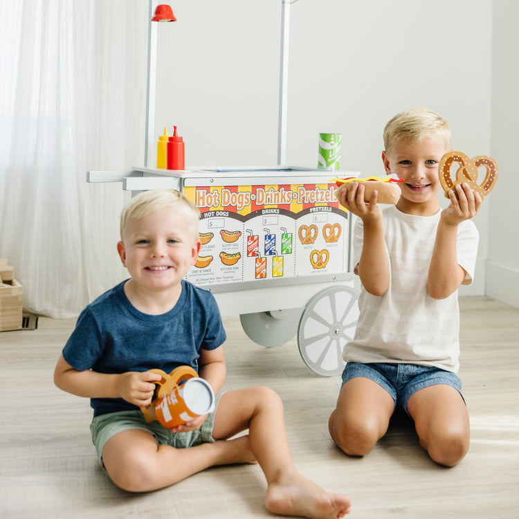 A kid playing with The Melissa & Doug Wooden Snacks and Sweets Food Cart - 40+ Play Food pcs, Reversible Awning