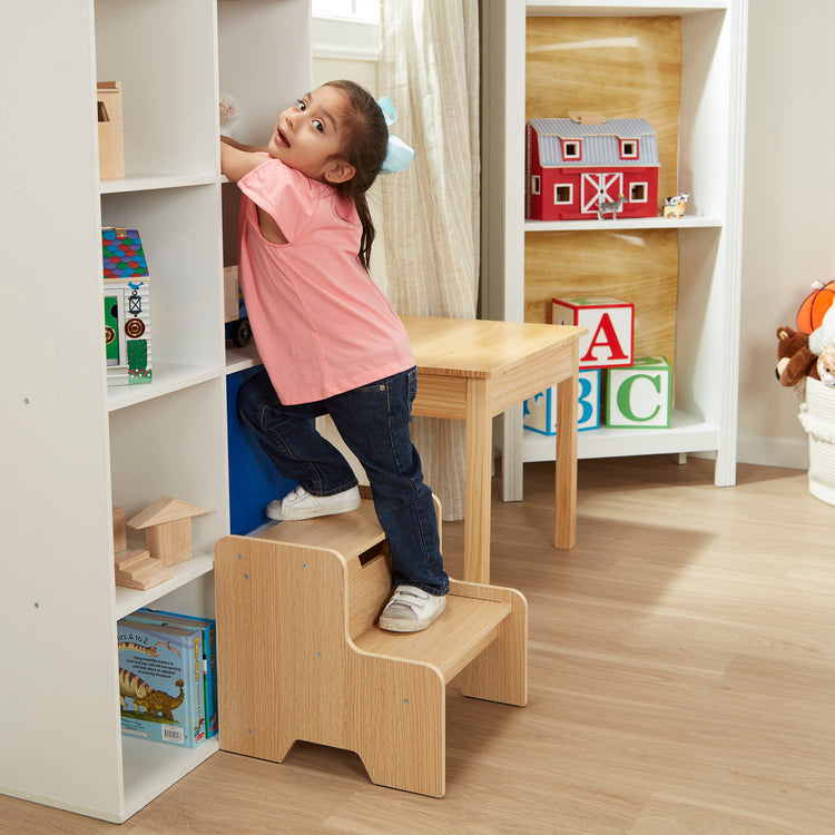 A kid playing with The Melissa & Doug Kids Wooden Step Stool - Light Natural Finish