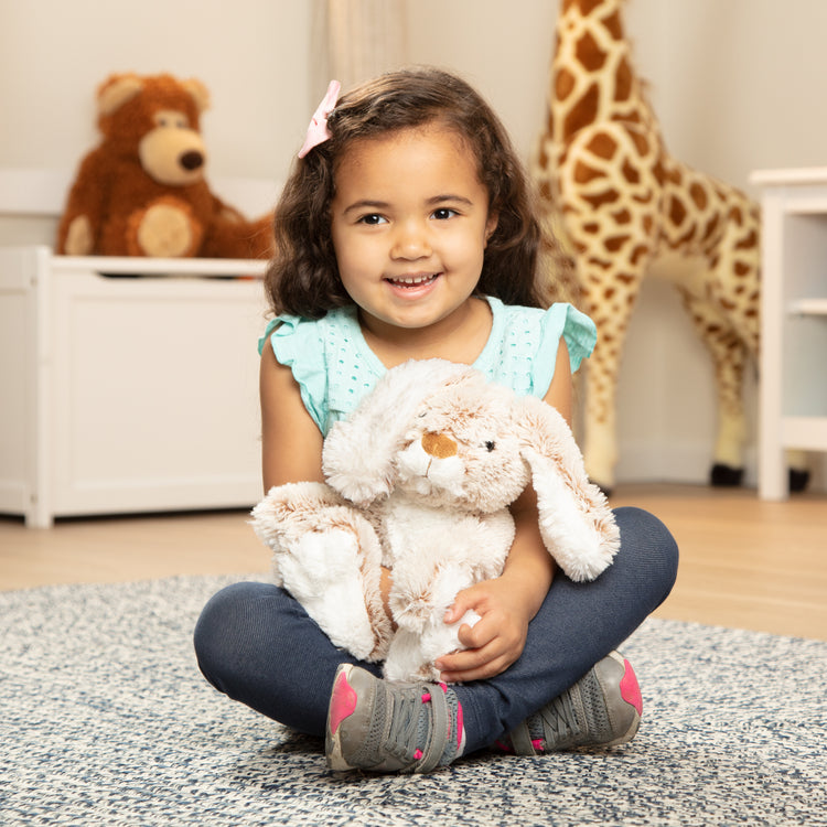 A child on white background with The Melissa & Doug Burrow Bunny Rabbit Stuffed Animal (9 inches)