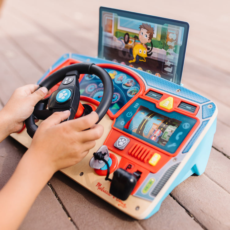 A kid playing with The Melissa & Doug PAW Patrol Rescue Mission Wooden Dashboard