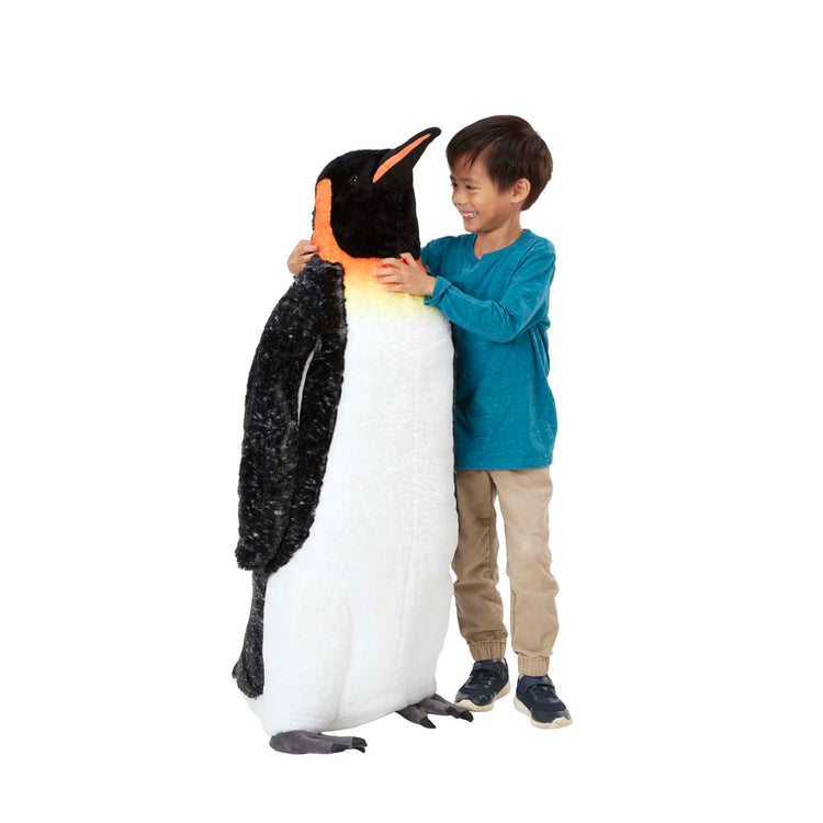 A child on white background with The Melissa & Doug Giant Lifelike Plush Emperor Penguin Standing Stuffed Animal (3.4 Feet Tall)