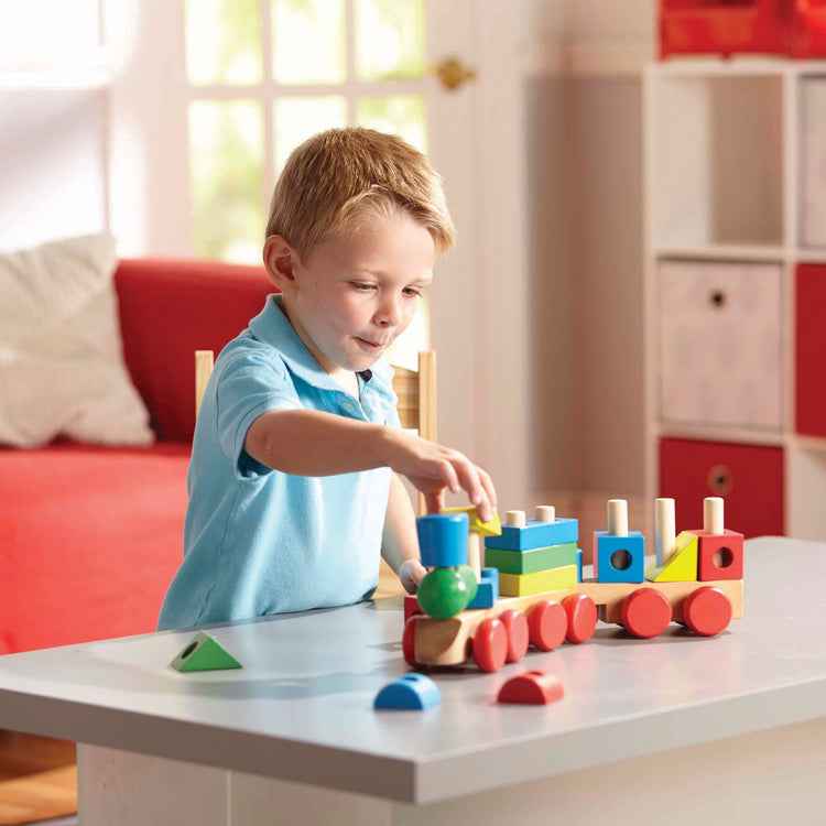 A kid playing with The Melissa & Doug Wooden Stacking Train Learning Toy Vehicle With 18 Connecting Pcs