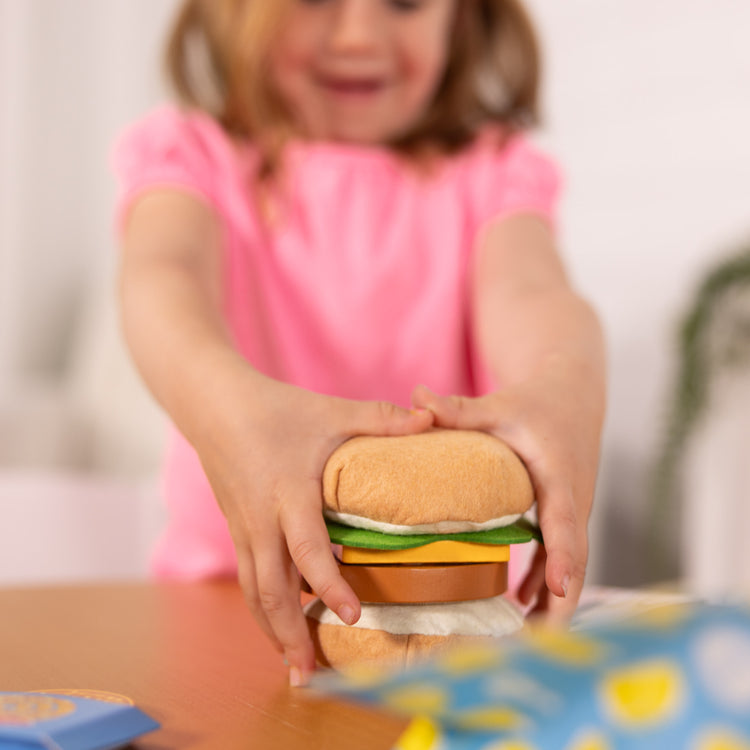 A kid playing with The Melissa & Doug What’s for Lunch?™ Surprise Meal Play Food Set Series 2