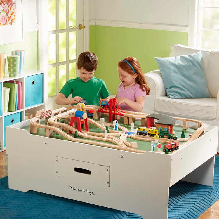 A kid playing with the Melissa & Doug Deluxe Wooden Multi-Activity Play Table - For Trains, Puzzles, Games, More